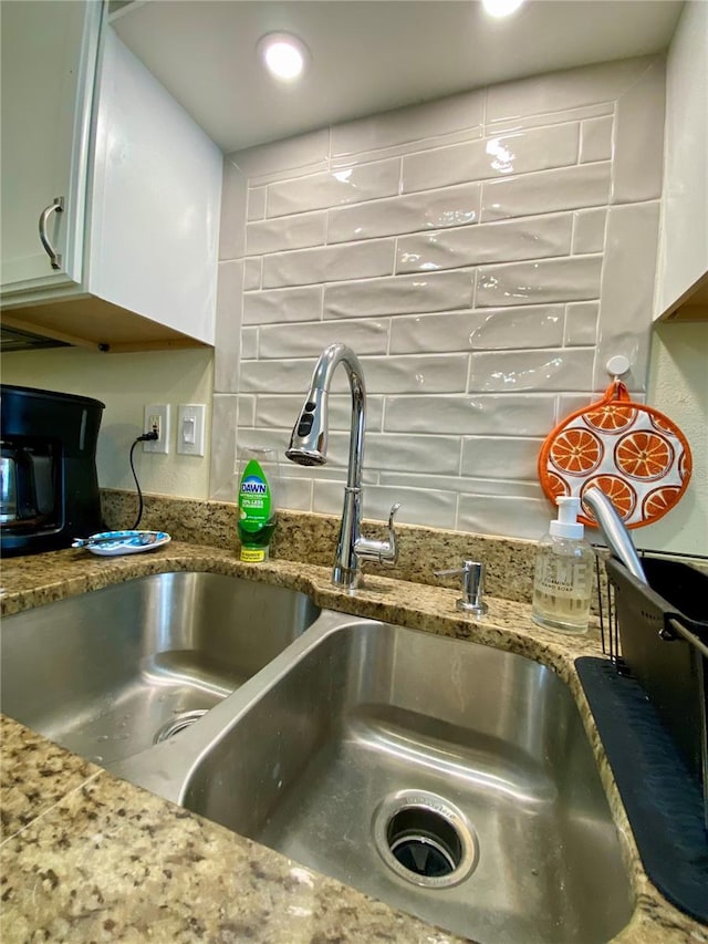 details with stone countertops, white cabinetry, and sink