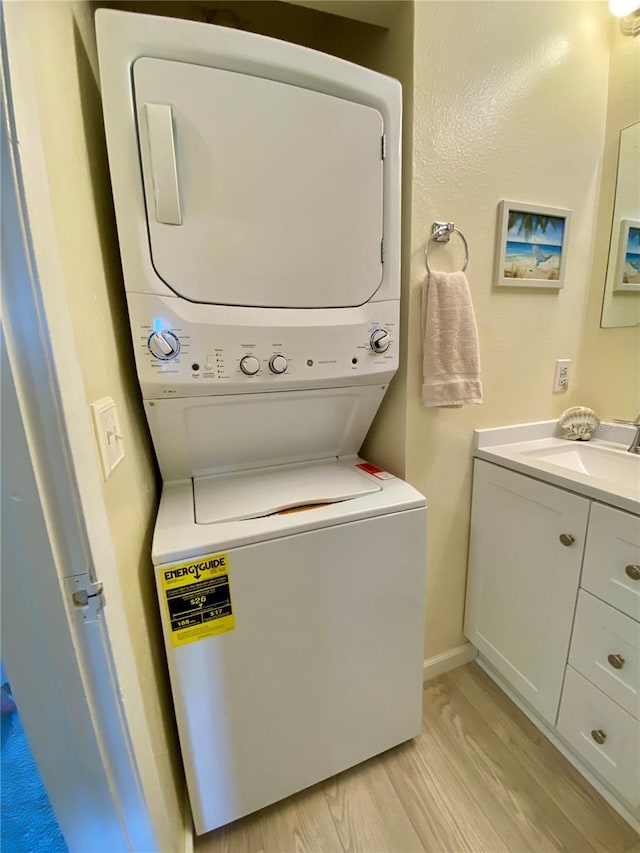 washroom featuring light hardwood / wood-style flooring, stacked washing maching and dryer, and sink