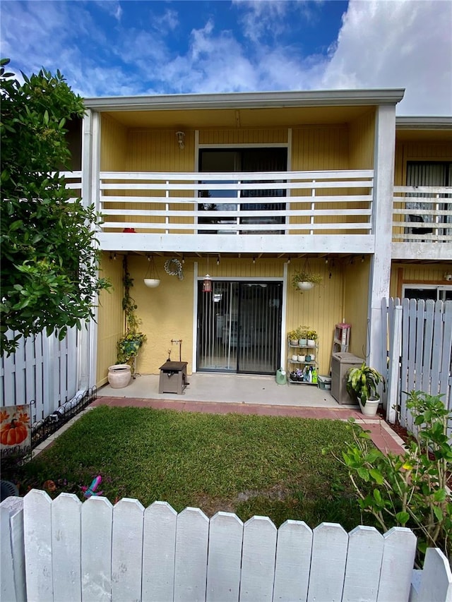 back of house with a balcony, a yard, and a patio