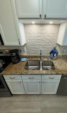 kitchen with dark stone countertops, sink, and white cabinets