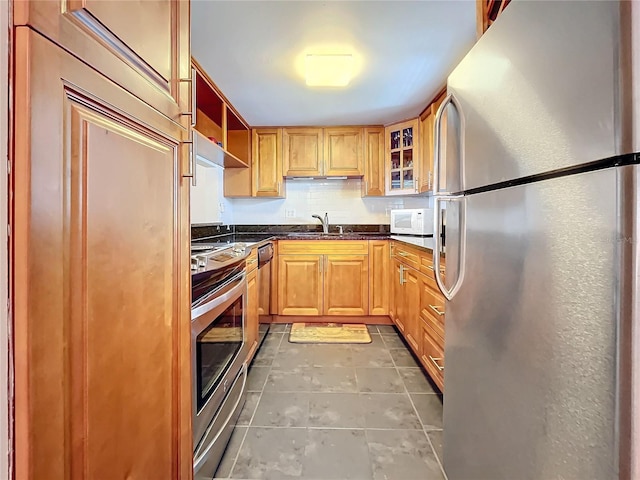 kitchen with dark tile patterned flooring, stainless steel appliances, sink, and tasteful backsplash