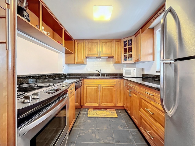 kitchen with stainless steel appliances, dark stone countertops, sink, and decorative backsplash