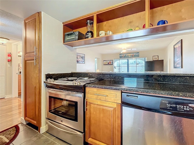 kitchen with dark stone countertops, light tile patterned floors, and appliances with stainless steel finishes