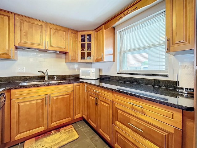 kitchen featuring dark stone counters, dark tile patterned floors, sink, decorative backsplash, and stainless steel dishwasher