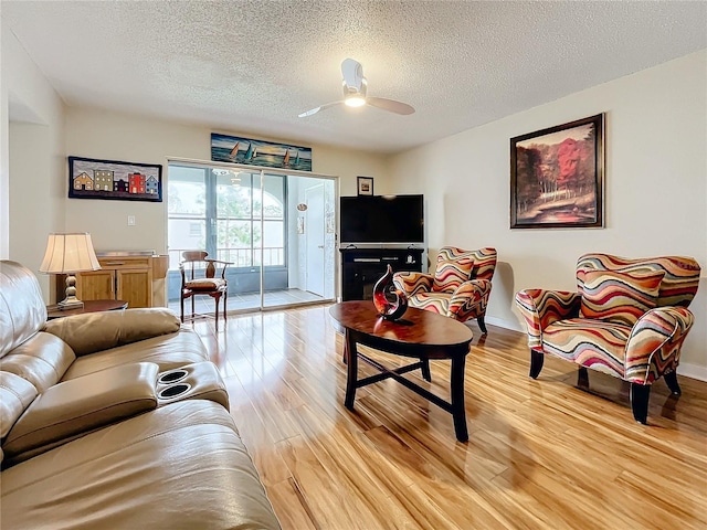 living room featuring ceiling fan, a textured ceiling, and light hardwood / wood-style flooring