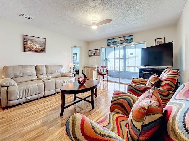 living room featuring ceiling fan, a textured ceiling, and light hardwood / wood-style flooring