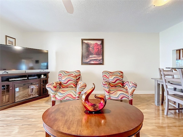 dining room with light hardwood / wood-style floors, ceiling fan, and a textured ceiling