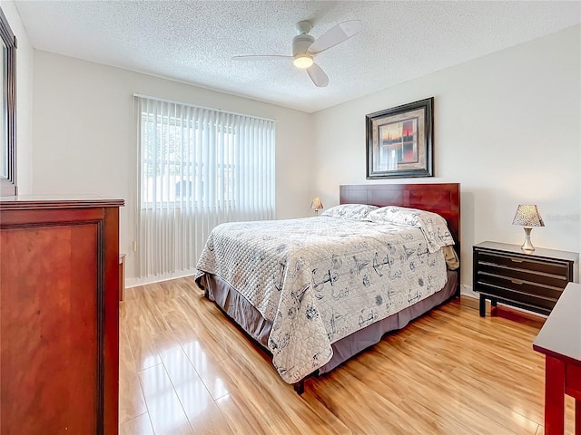 bedroom with hardwood / wood-style floors, ceiling fan, and a textured ceiling