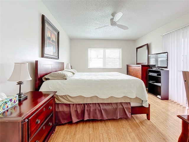 bedroom with a textured ceiling, light hardwood / wood-style flooring, and ceiling fan