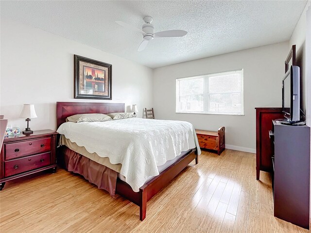 bedroom featuring light hardwood / wood-style floors, ceiling fan, and a textured ceiling