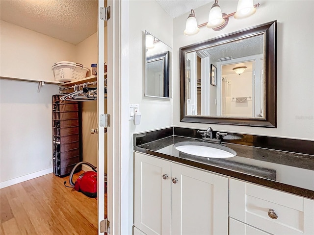 bathroom with hardwood / wood-style floors, vanity, and a textured ceiling