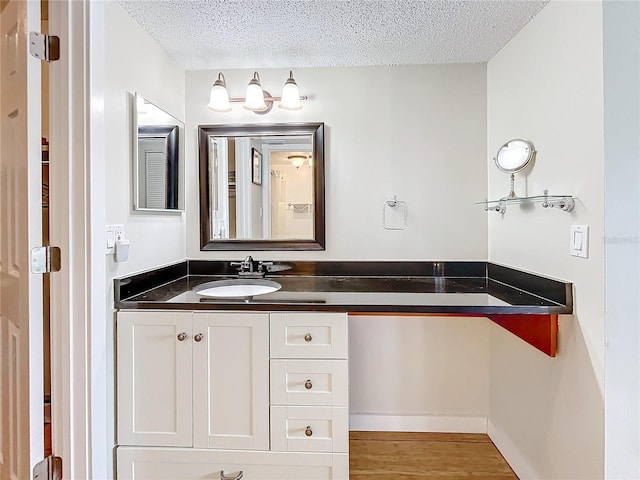 bathroom with hardwood / wood-style floors, vanity, and a textured ceiling