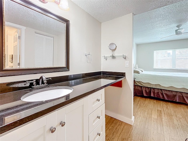 bathroom with wood-type flooring, a textured ceiling, ceiling fan, and vanity