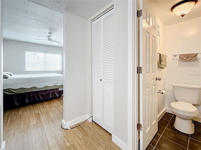 bathroom featuring wood-type flooring, a textured ceiling, toilet, and ceiling fan