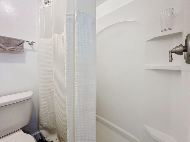 bathroom with toilet and a shower with shower curtain