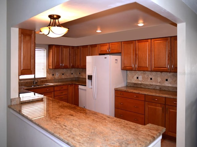 kitchen featuring decorative backsplash, white appliances, sink, and light stone counters