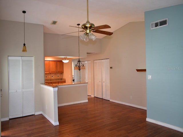 kitchen with kitchen peninsula, dark hardwood / wood-style flooring, ceiling fan, and high vaulted ceiling