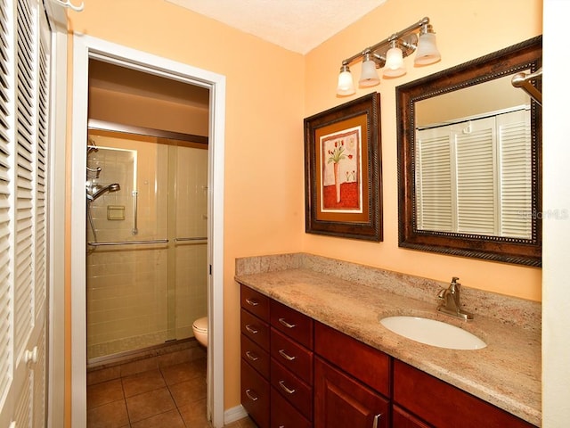 bathroom featuring vanity, walk in shower, tile patterned flooring, and toilet