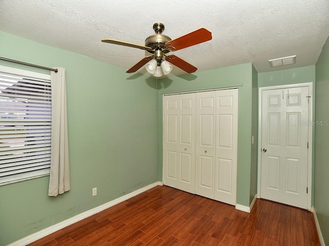 unfurnished bedroom featuring ceiling fan, dark hardwood / wood-style floors, and a textured ceiling