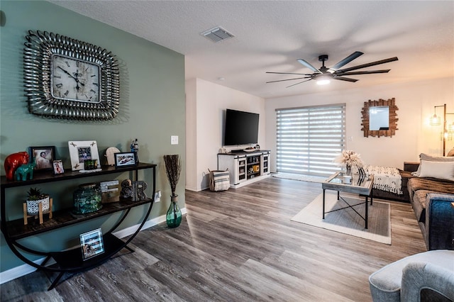 living room featuring ceiling fan, wood-type flooring, and a textured ceiling