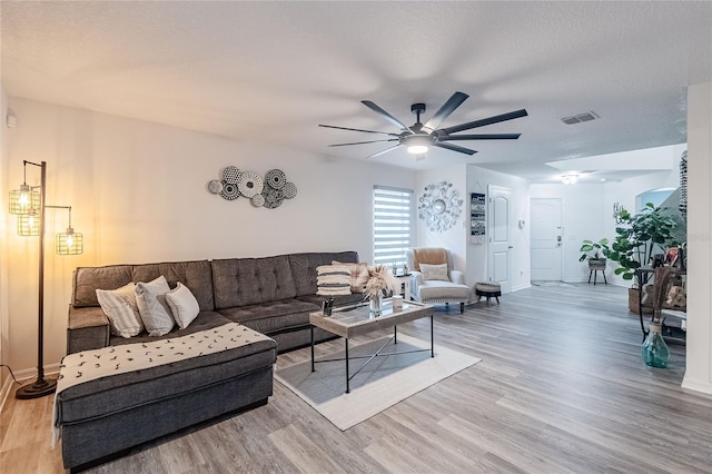 living room with ceiling fan, wood-type flooring, and a textured ceiling