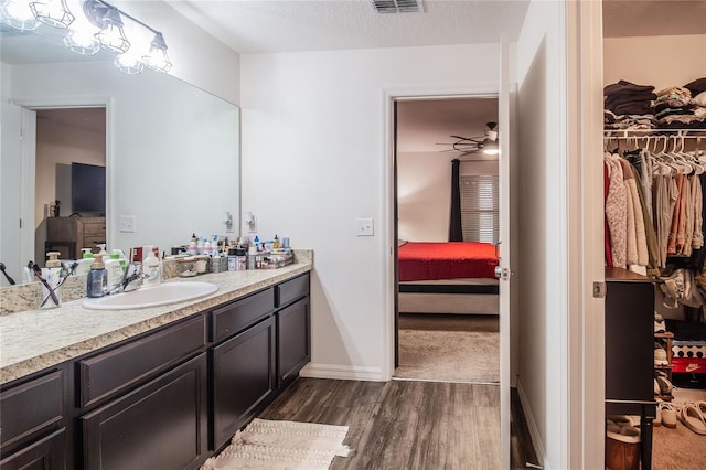 bathroom featuring ceiling fan, wood-type flooring, vanity, and a textured ceiling