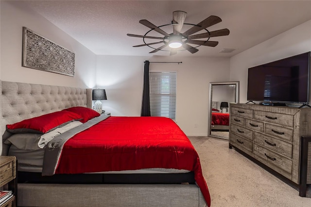 bedroom with a textured ceiling, light colored carpet, and ceiling fan