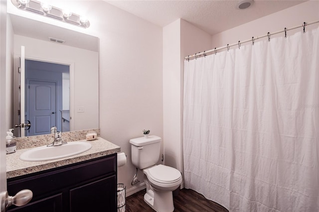 bathroom featuring hardwood / wood-style flooring, a textured ceiling, curtained shower, vanity, and toilet