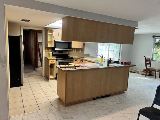 kitchen with tasteful backsplash, appliances with stainless steel finishes, light brown cabinets, sink, and kitchen peninsula