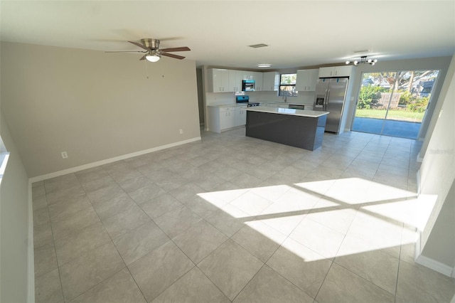 kitchen with ceiling fan, white cabinetry, light tile patterned floors, a kitchen island, and appliances with stainless steel finishes