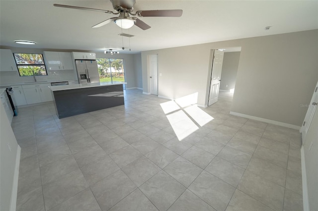 kitchen with plenty of natural light, white cabinets, stainless steel refrigerator with ice dispenser, and a kitchen island