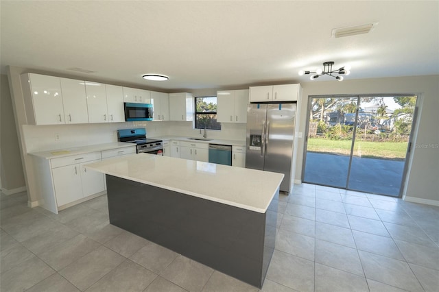 kitchen featuring a center island, sink, light tile patterned floors, white cabinetry, and stainless steel appliances