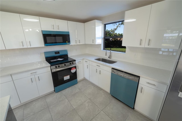 kitchen with decorative backsplash, appliances with stainless steel finishes, sink, white cabinetry, and light tile patterned flooring