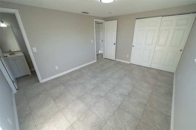 unfurnished bedroom featuring connected bathroom, a closet, and sink