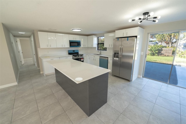 kitchen featuring sink, a center island, an inviting chandelier, white cabinets, and appliances with stainless steel finishes