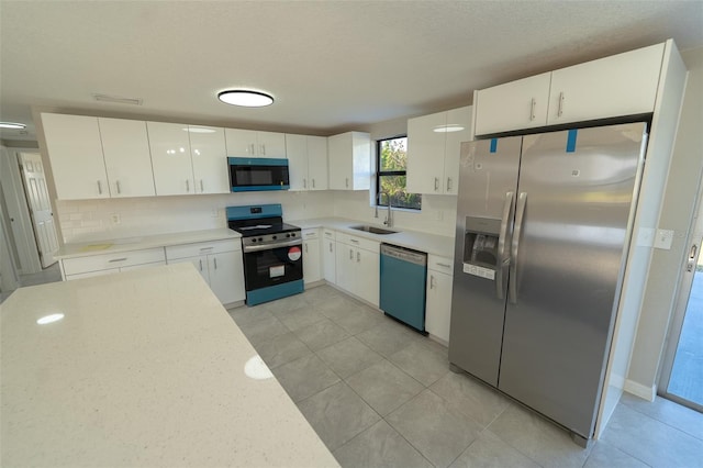 kitchen with white cabinetry, sink, stainless steel appliances, tasteful backsplash, and light tile patterned floors