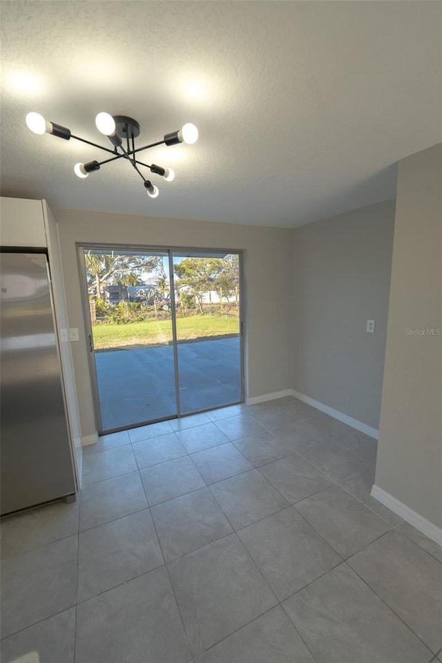 tiled empty room featuring a chandelier and a textured ceiling