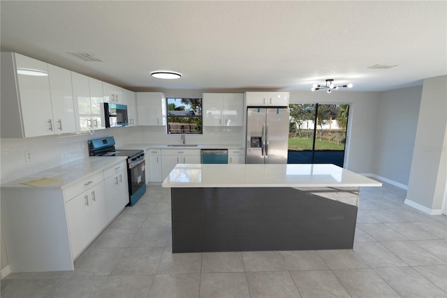 kitchen featuring white cabinets, sink, appliances with stainless steel finishes, tasteful backsplash, and a kitchen island