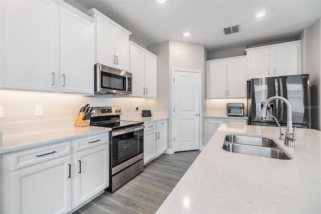 kitchen featuring light wood-type flooring, appliances with stainless steel finishes, sink, and white cabinets