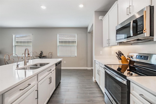 kitchen with dark hardwood / wood-style flooring, white cabinets, sink, and stainless steel appliances