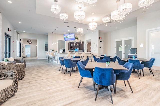 dining space featuring french doors, light hardwood / wood-style flooring, and a chandelier