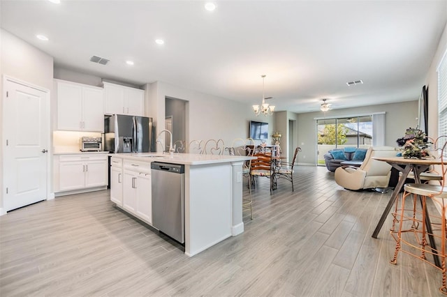 kitchen featuring white cabinets, a center island with sink, light hardwood / wood-style flooring, and appliances with stainless steel finishes