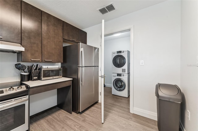 kitchen featuring light hardwood / wood-style floors, stacked washer / dryer, premium range hood, and appliances with stainless steel finishes