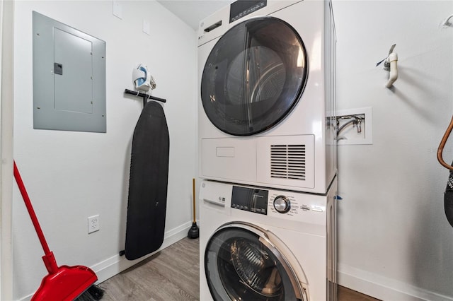 washroom featuring electric panel, light hardwood / wood-style flooring, and stacked washer and clothes dryer