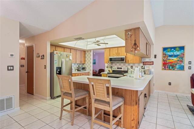 kitchen with ceiling fan, a kitchen breakfast bar, kitchen peninsula, decorative backsplash, and appliances with stainless steel finishes