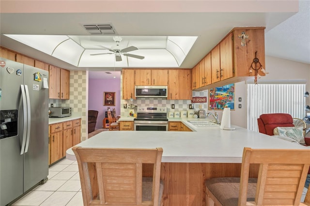 kitchen featuring sink, decorative backsplash, light tile patterned floors, appliances with stainless steel finishes, and kitchen peninsula