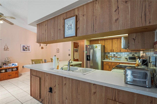 kitchen with decorative backsplash, stainless steel fridge, kitchen peninsula, ceiling fan, and light tile patterned floors