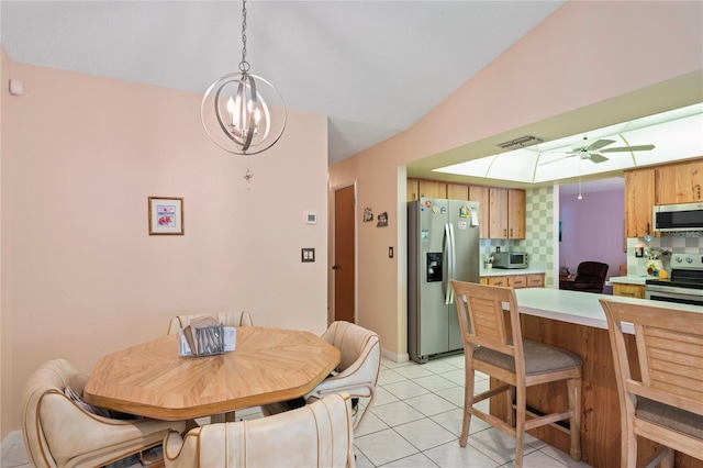 tiled dining area featuring ceiling fan with notable chandelier and lofted ceiling