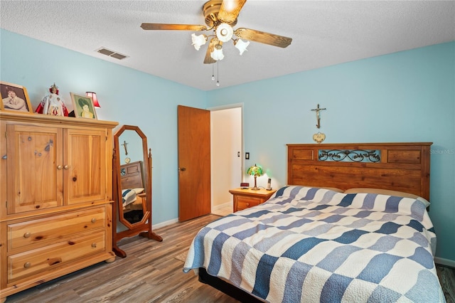 bedroom with a textured ceiling, hardwood / wood-style flooring, and ceiling fan