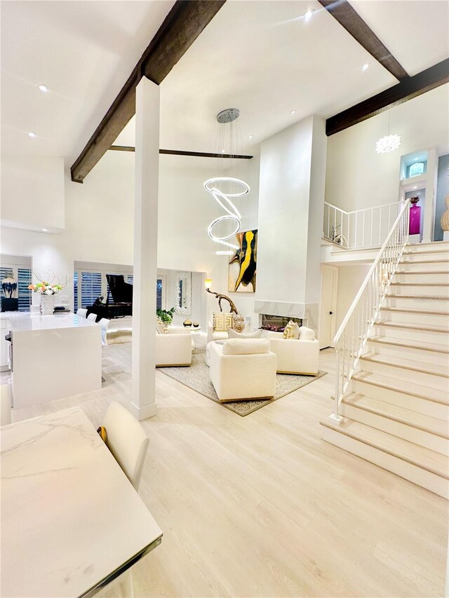 living room featuring a chandelier, light wood-type flooring, and a towering ceiling